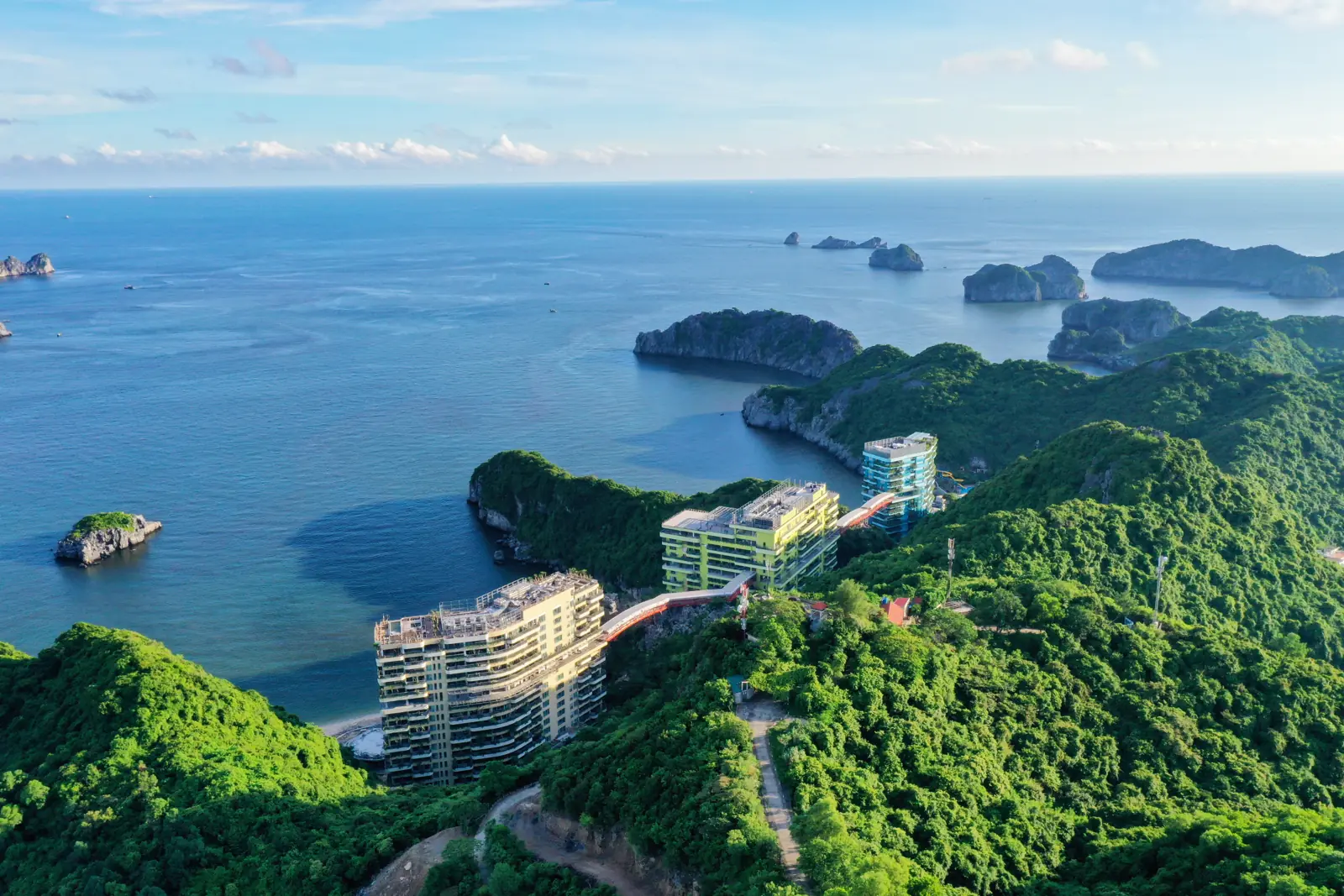 Các tòa nhà Flamingo Cát Bà trên sườn núi phủ rừng bên bờ biển đảo Cát Bà, phía xa là các đảo đá vôi giữa vịnh