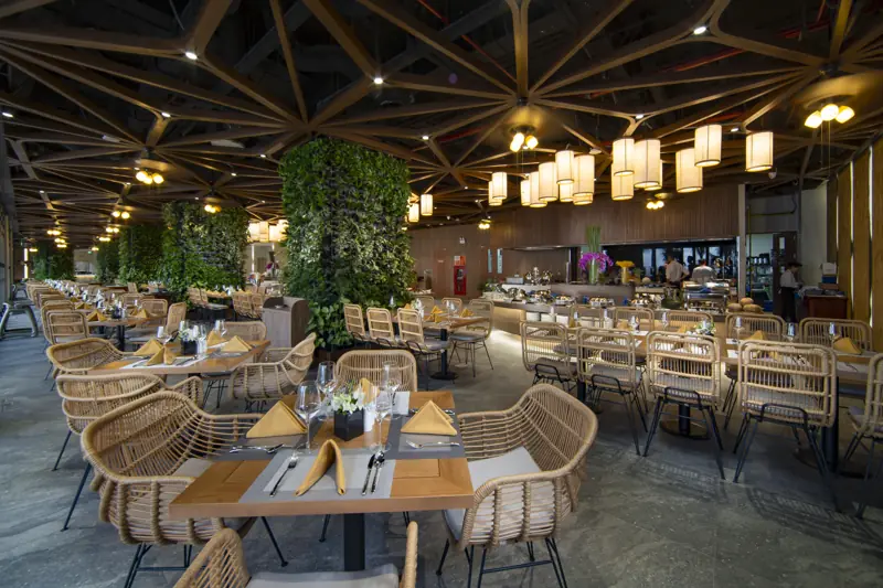 Nhà hàng buffet ở Flamingo Cát Bà với đèn lồng treo, cột cây xanh và bàn ghế mây