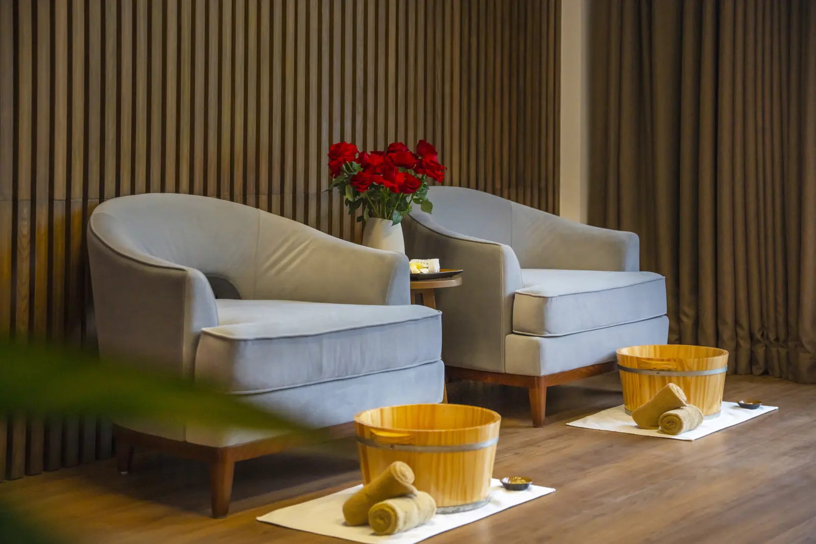 Hai ghế bành và hai chậu gỗ ngâm chân kèm khăn cuộn ở SEVA Onsen & Spa Flamingo Cát Bà