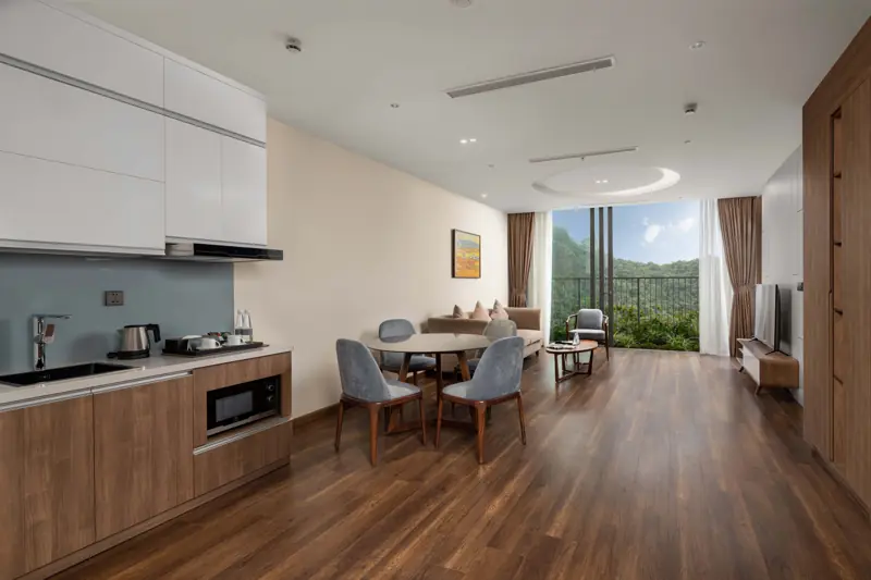 Phòng khách liền bếp nhỏ và bàn ăn trong căn Residence 1 phòng ngủ Flamingo Cát Bà, cửa kính nhìn ra núi