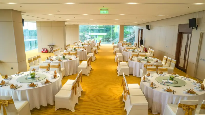 Sand Ballroom bày hai dãy bàn tròn phủ khăn trắng, sàn thảm vàng, cửa kính cuối phòng nhìn ra cây xanh