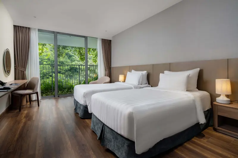 Phòng Deluxe Mountain View: hai giường đơn, cửa kính lớn nhìn ra cây xanh trên núi