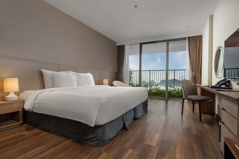 Phòng Deluxe Ocean View: giường đôi, cửa kính ra ban công nhìn biển và núi đá