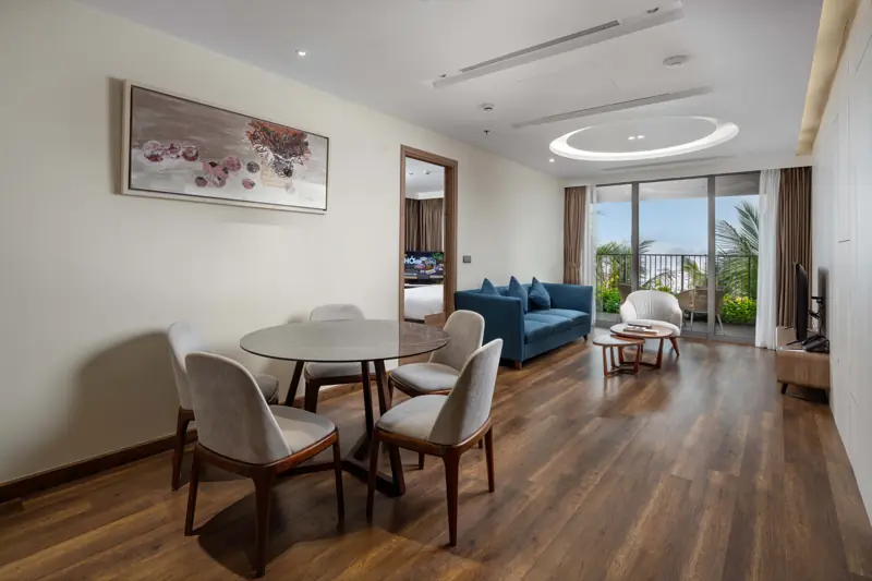 Căn Premier Residence 3 phòng ngủ: bàn ăn tròn, phòng khách sofa xanh và cửa kính ra ban công
