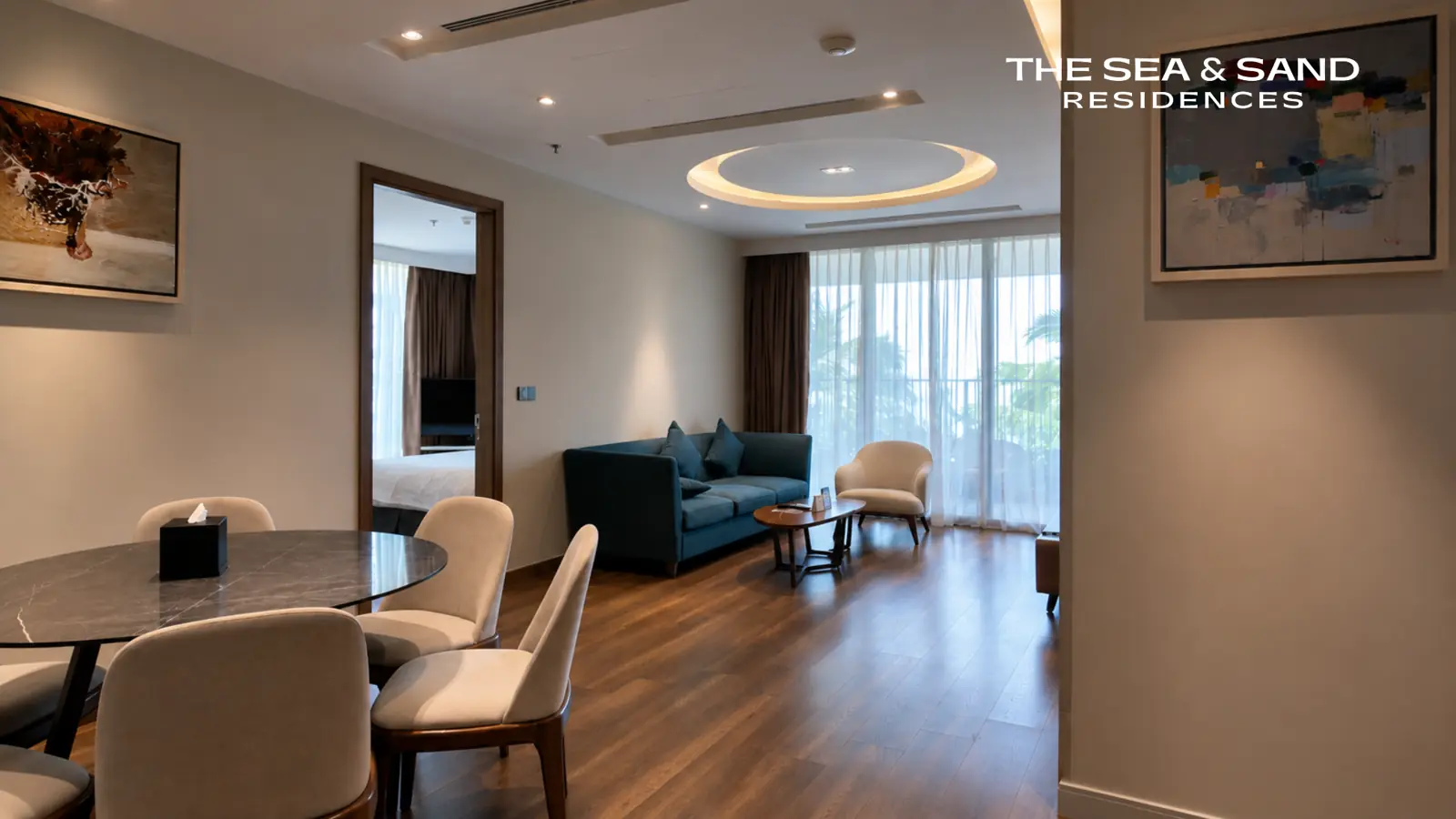 Phòng khách và bàn ăn trong một căn The Sea & Sand Residences, cửa kính lớn nhìn ra ngoài