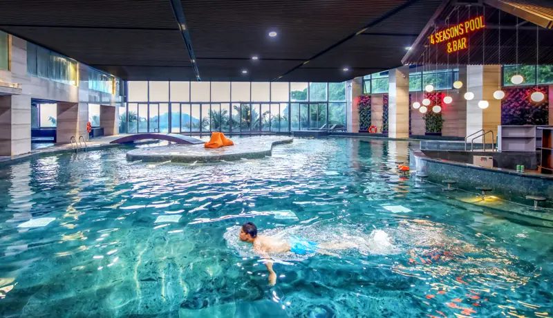Bể bơi bốn mùa trong nhà có vách kính nhìn ra vịnh, cạnh quầy bar
