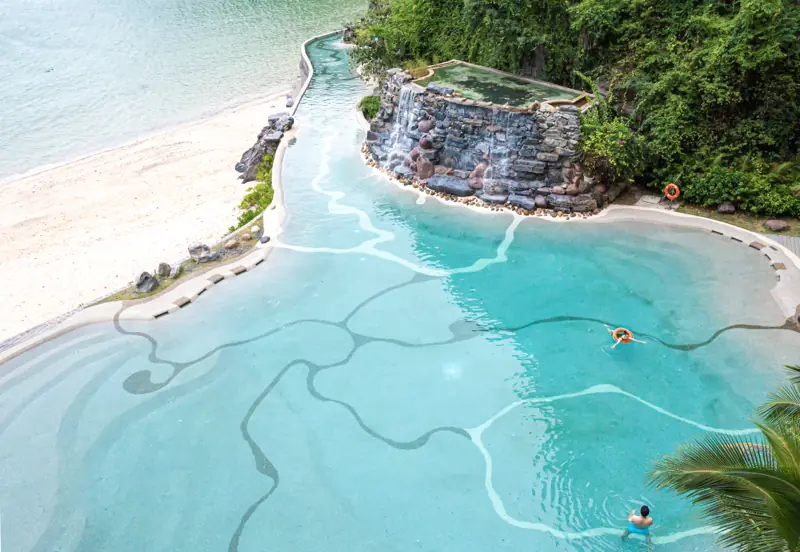 Bể bơi ngoài trời Charm Pool uốn quanh vách đá có thác nước nhỏ, sát bãi cát Cát Cò