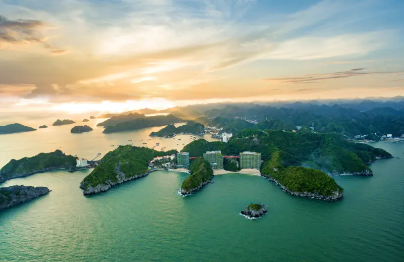 Vịnh Lan Hạ lúc hoàng hôn với nhiều đảo đá vôi phủ rừng, nhìn từ trên cao về phía bãi Cát Cò
