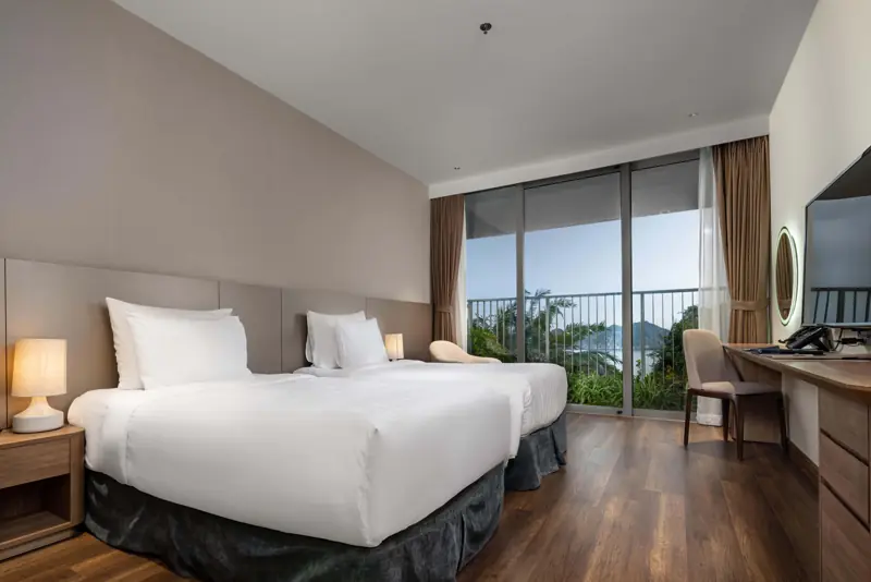 Phòng Deluxe Ocean View hai giường đơn, cửa kính mở ra ban công nhìn biển