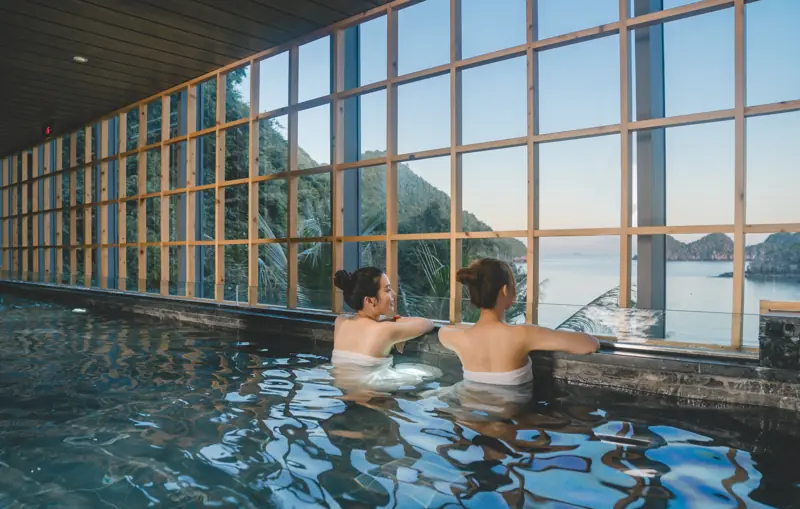 Bể onsen trong nhà ở SEVA Onsen & Spa, vách kính lớn nhìn ra vịnh Lan Hạ